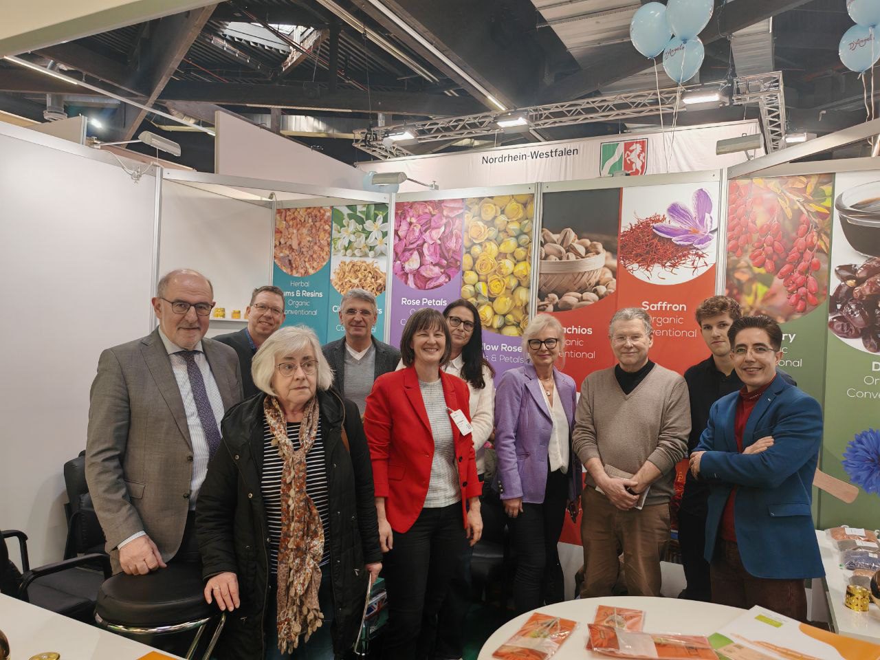 Besucher des Blumental Bayern stehen vor einer farbenfrohen Ausstellung aus Bio-Safran und Rosenblättern auf einer Gesundheitsmesse.