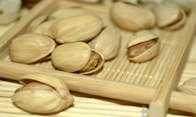 Roasted pistachios on a bamboo tray, representing high-quality organic products for a natural health lifestyle.