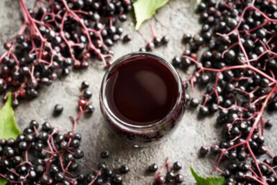 Dark elderberry juice in a glass with fresh berries, highlighting organic products for natural health and a wellness lifestyle.