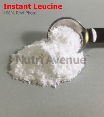 Ein Häufchen feines weißes Pulver mit der Aufschrift „Instant Leucin“ neben einem mit dem Pulver gefüllten Messlöffel aus Metall.
